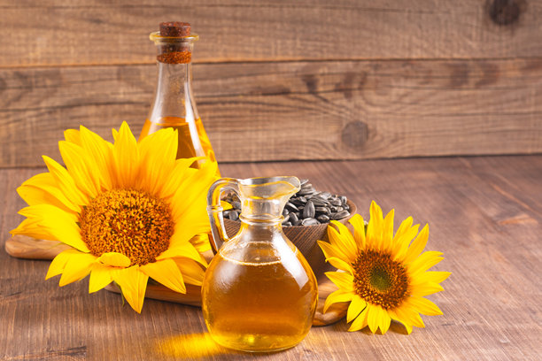 向日葵油的特写照片，背景为木质表面，旁边有种子。生物和有机产品概念。图片下载