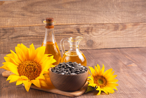 向日葵油的特写照片，背景为木质表面，旁边有种子。生物和有机产品概念。图片下载