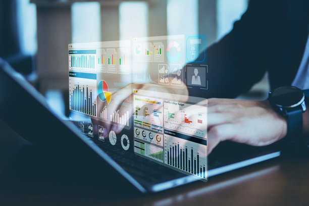 黑暗色调的照片，展示一位商人在笔记本电脑上工作，投影出图表、柱状图和实时业务绩效指标的界面。高科技商业环境概念。图片下载