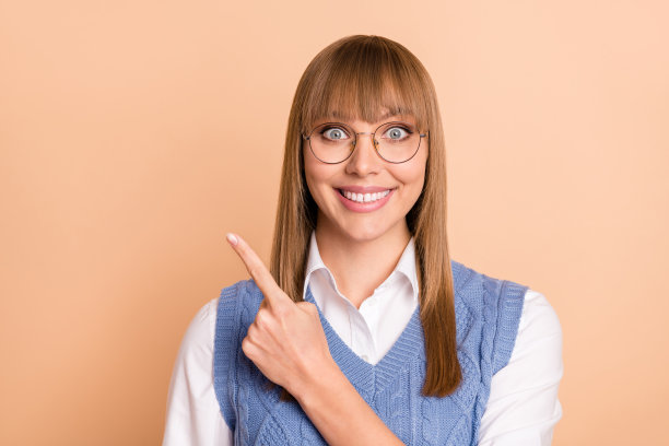 微笑的女学生在淡米色背景上指着空白区域的照片肖像图片下载