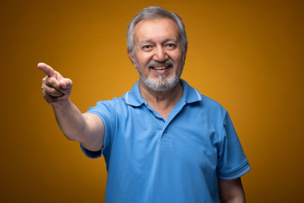 穿着蓝色T恤的老年帅气男性肖像照片，背景为黄色。图片下载