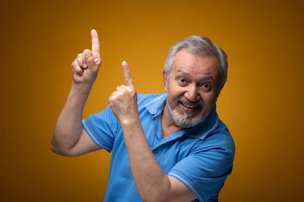 穿着蓝色T恤的老年帅气男性肖像照片，背景为黄色。图片下载
