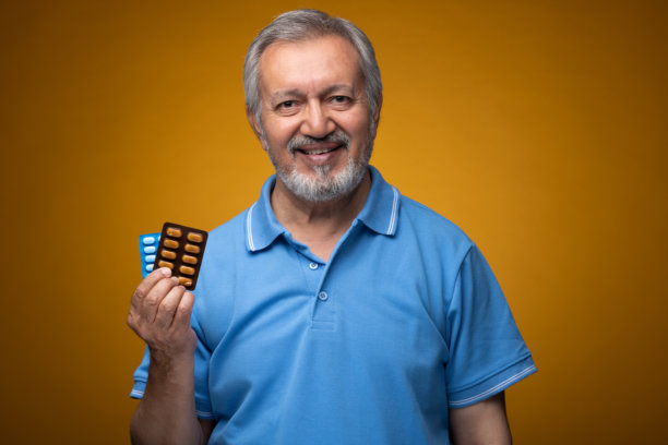 穿着蓝色T恤的老年帅气男性肖像照片，背景为黄色。图片下载