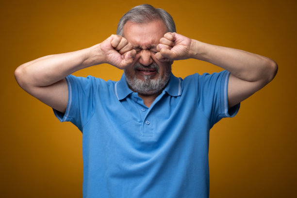 穿着蓝色T恤的老年帅气男性肖像照片，背景为黄色。图片下载