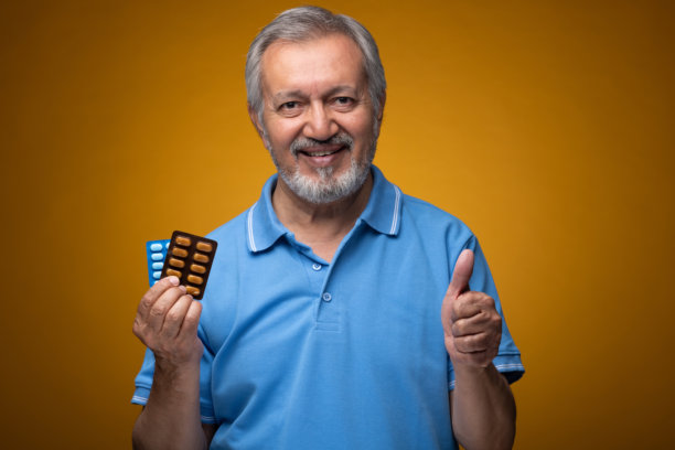 穿着蓝色T恤的老年帅气男性肖像照片，背景为黄色。图片下载