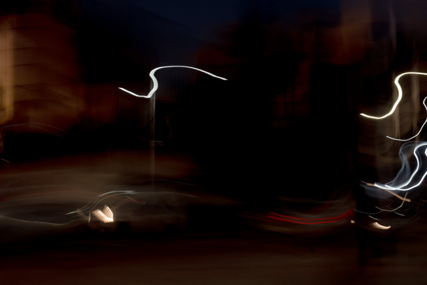 夜晚的建筑大道照片，色彩斑斓的条纹。这些条纹是汽车灯光和街灯的倒影。照片营造出一种黑暗而神秘的氛围。图片下载