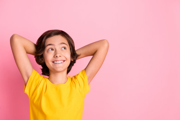 高角度俯视照片，快乐放松的小男孩在粉色背景上看向空旷的空间，享受周末时光。图片下载