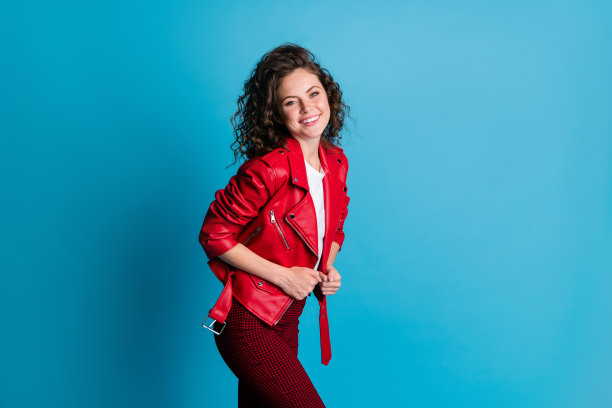 乐观女孩穿着红色夹克和裤子，背景为蓝色，个人头像照片图片下载