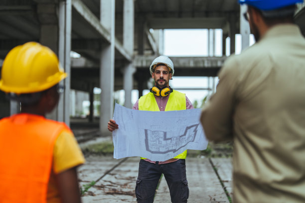 一群建筑师在建筑工地上使用蓝图的照片图片下载