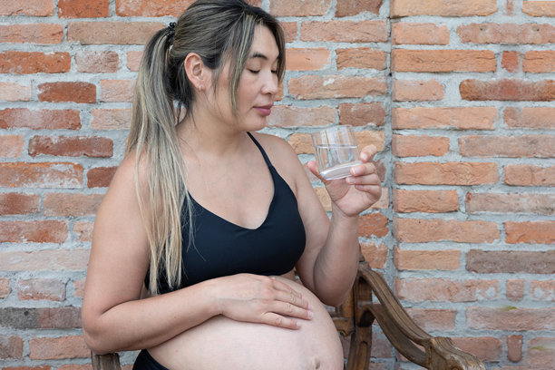 孕妇喝水并抚摸肚子图片下载