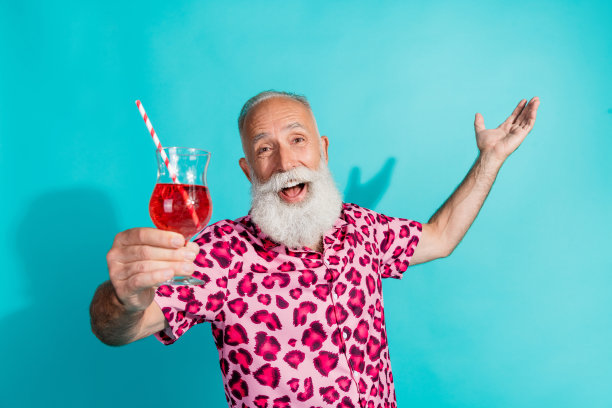 穿着豹纹服装的搞笑老年男子在青色背景下喝鸡尾酒的照片图片下载