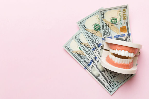 特写的人类下颌模型，白色牙齿和美元钞票。牙科概念照片。义齿。假牙的俯视图，留有空白空间。图片下载