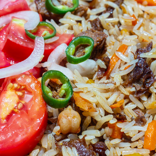 一盘米饭配肉，装饰有切碎的番茄、洋葱和辣青椒沙拉。此照片适合餐饮业和任何与食品相关的设计。图片下载