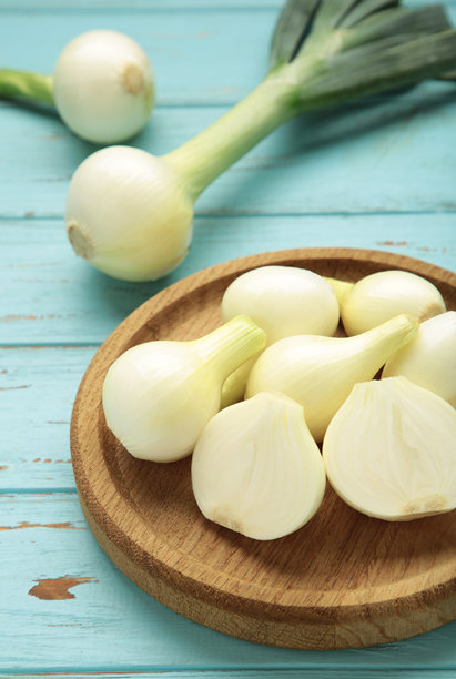 蓝色木背景上的木盘中的青葱。竖版照片图片下载