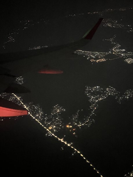 这张图片捕捉了从飞机窗座看到的夜景，机翼上可见的飞机注册号表明了这一点。图片下载