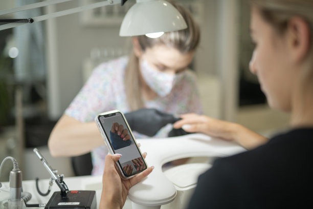 客户正在查找指甲设计的参考照片，以便向美甲师展示。图片下载