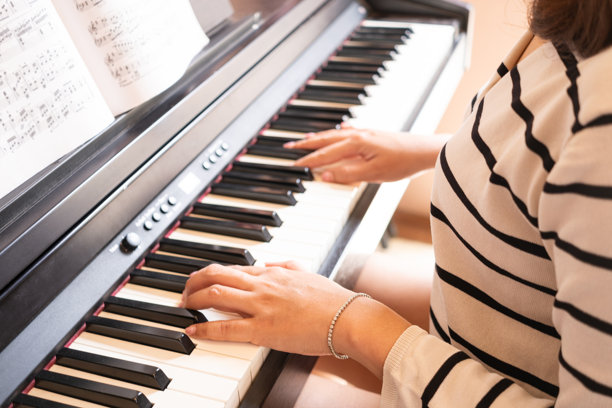 女人的手在弹钢琴，她用音乐来放松和缓解压力。看音乐家的特写照片。爱好的概念图片下载