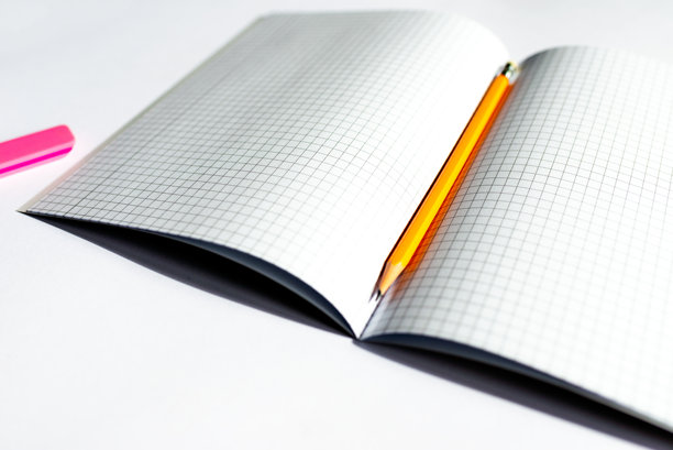 笔记本的俯视图照片，上面有格子页，上面有黄色的铅笔和粉红色的橡皮擦。图片下载