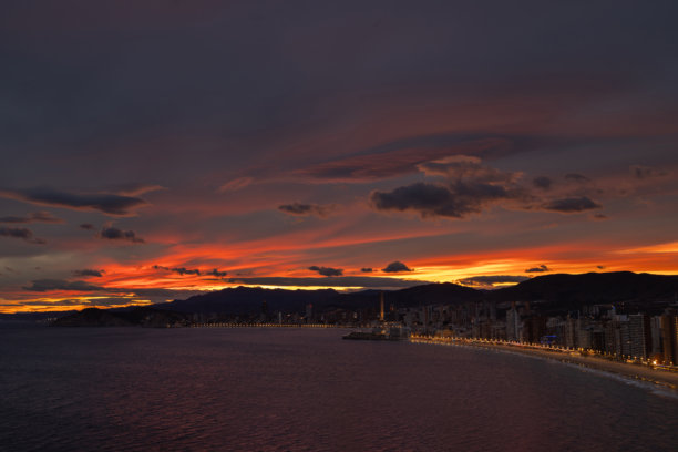 这是西班牙贝尼多姆著名的莱万特海滩的航拍照片，显示了夏季太阳落在山后的海滩。图片下载