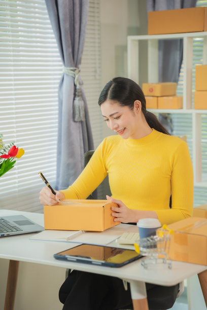 亚洲女性送货概念，自由职业，网上购物，在家用笔记本电脑与包裹箱工作，在线中小企业，竖版照片。图片下载