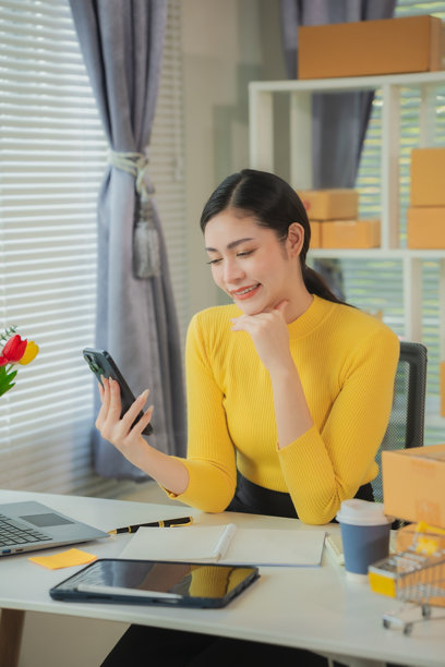 亚洲女性送货概念，自由职业，在线购物，在家中使用笔记本电脑与包裹箱，在线中小企业，竖版照片。图片下载