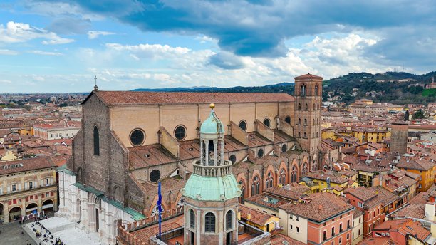 从侧面俯瞰圣彼得罗尼乌斯大教堂，前景是圆顶钟楼的阿库尔索宫，背景是阿伦戈塔，博洛尼亚历史中心，适合文化遗产和旅行视觉素材。图片下载