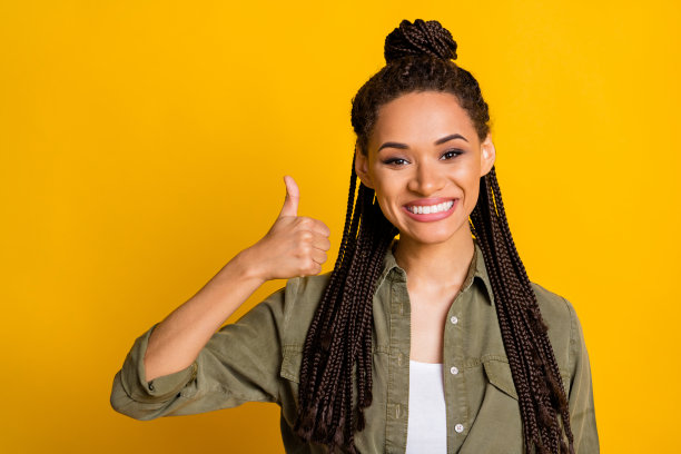 酷女孩在鲜艳的黄色背景下竖起大拇指的照片肖像图片下载