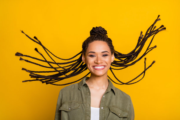 女孩的照片肖像，飞扬的头发，背景为鲜艳的黄色图片下载