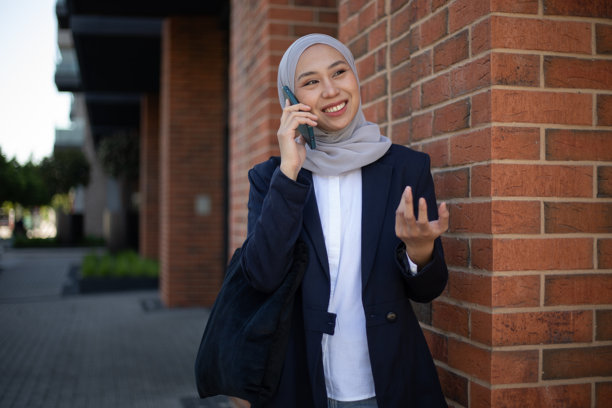 微笑的女商人戴着头巾正在打电话。库存图片图片下载