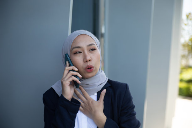 穆斯林女商人接电话时对消息感到惊讶。库存图片图片下载