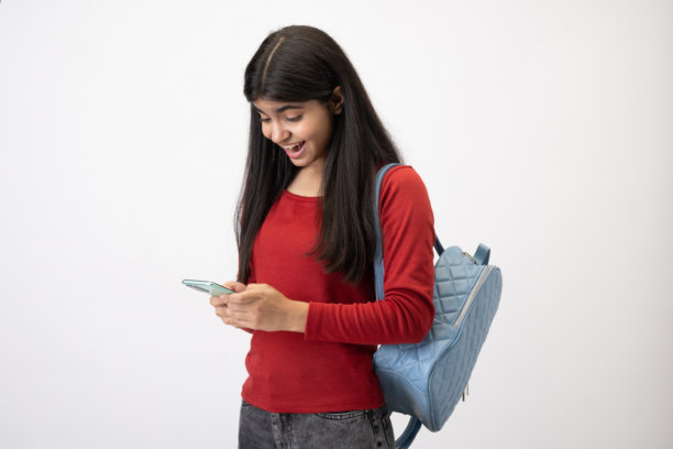 穿着休闲T恤的漂亮少女在白色背景下使用手机的照片图片下载