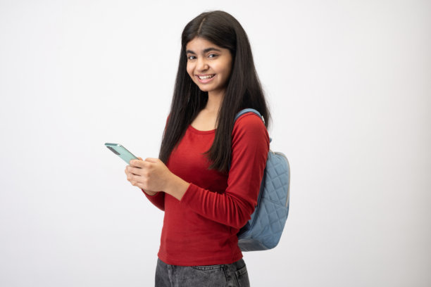 穿着休闲T恤的漂亮少女在白色背景下使用手机的照片图片下载