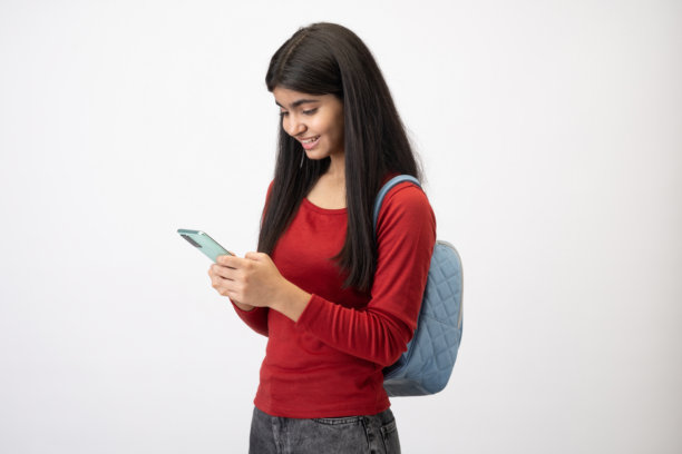 穿着休闲T恤的漂亮少女在白色背景下使用手机的照片图片下载