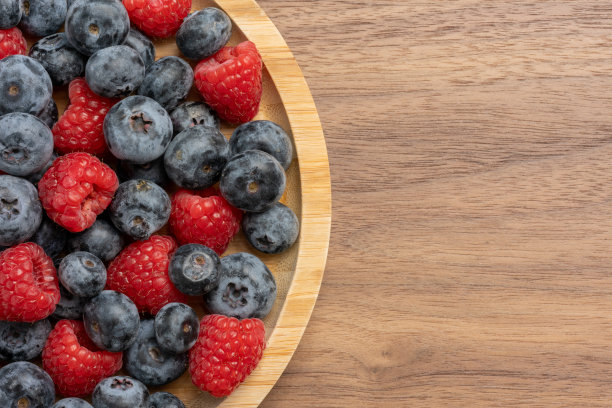 高分辨率的混合水果照片，包括樱桃、覆盆子和蓝莓，摆放在盘子上，采用了分离焦点技术拍摄。图片下载