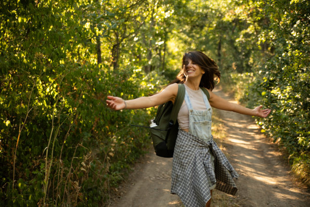 年轻女性在大自然中张开双臂徒步旅行，享受新鲜空气。库存照片图片下载