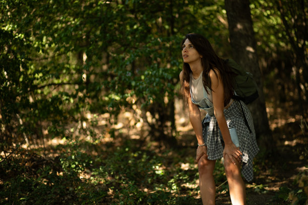 疲惫的徒步旅行者在森林中艰难跋涉时休息。库存照片图片下载
