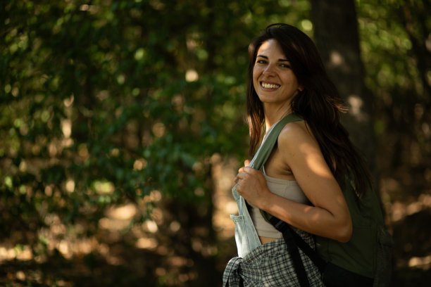 年轻女性在森林中徒步旅行并微笑。库存照片图片下载