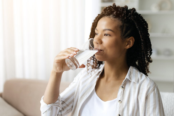 年轻孕妇坐在沙发上喝水图片下载