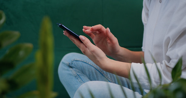 女性手部特写，手持手机，滑动在线应用中的照片并输入信息。年轻女孩在智能手机上浏览网页，社交网络中输入信息。图片下载