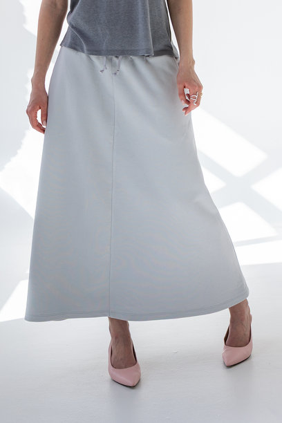 穿着灰色裙子和T恤的美丽女性，背景为白色。时尚女性风格。摄影棚拍摄。竖版照片。图片下载