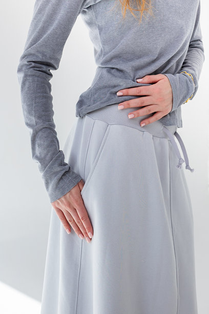 穿着灰色裙子和T恤的美丽女性，背景为白色。时尚女性风格。摄影棚拍摄。竖版照片。图片下载