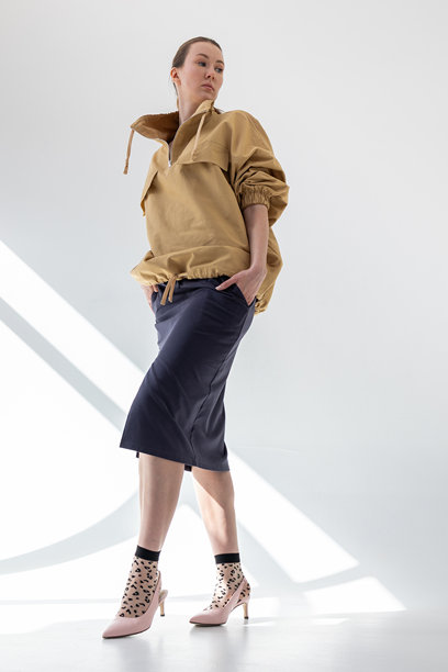 穿着米色风衣和黑色裙子的优雅女性，背景为白色。时尚女性风格。摄影棚拍摄。竖版照片。图片下载