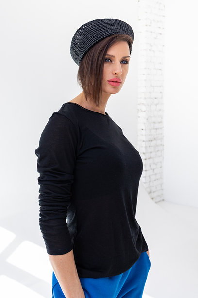 穿着黑色风衣夹克、蓝色裤子和海军帽的优雅女性，背景为白色。时尚女性展现海洋法式风格。摄影棚拍摄。竖版照片。图片下载