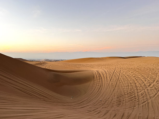 沙漠日出日落时分的照片，沙丘越野车轮胎在沙子上的痕迹图片下载