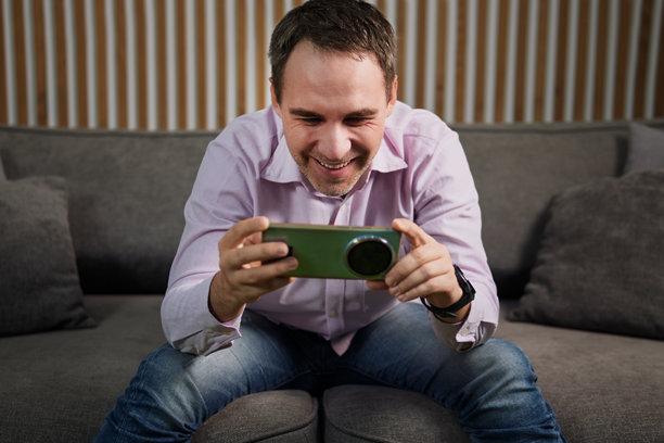 手持智能手机的快乐男人，正看着手机屏幕。正在手机上观看电影，享受晚间放松时光。图片下载