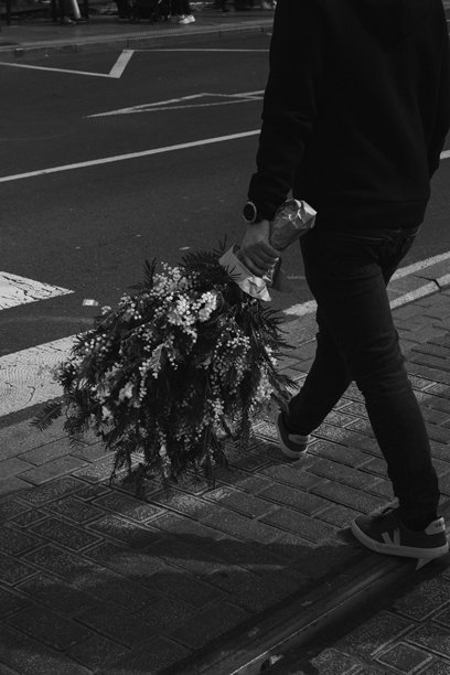 黑白照片中，一位匿名男子手持一束花走路。图片下载