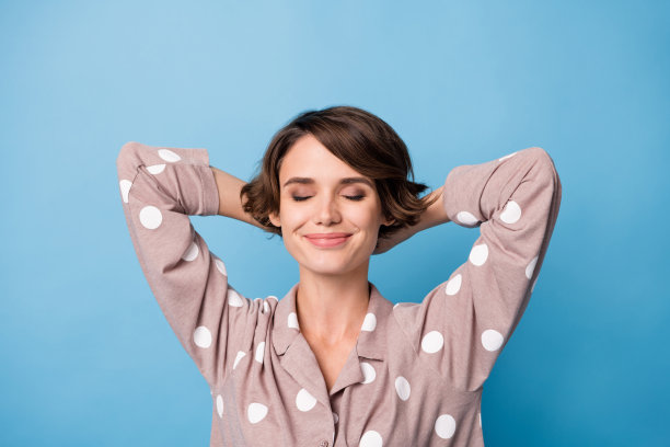 高角度俯视照片，快乐迷人的睡眠女性双手放在头后，背景为蓝色。图片下载