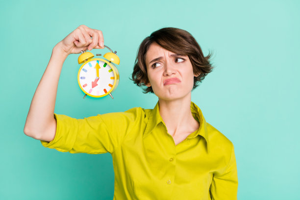 悲伤不快乐的女孩在明亮的青绿色背景下展示时钟截止日期的照片肖像图片下载