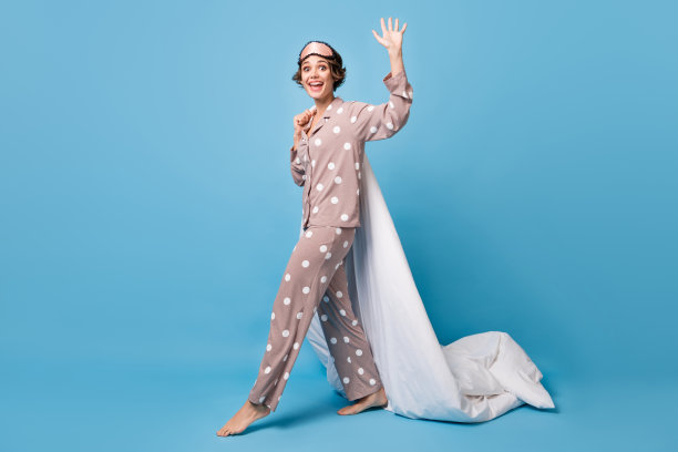 全身侧面照片的女性赤脚走在蓝色背景上，手持毯子，挥手问好，留有空白空间。图片下载