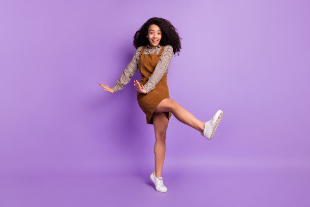 充满活力的非裔美国女孩在紫色背景下愉快地跳舞，面带微笑的全身照片图片下载